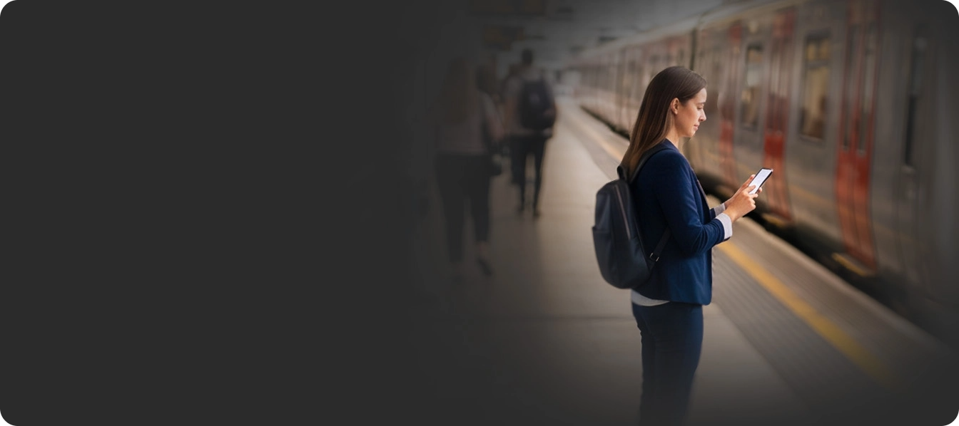 A commuter checking their phone at a train station